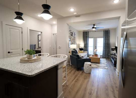 Open concept kitchen and living room with island seating at The Crest at South Point Apartments, McDonough, 30253