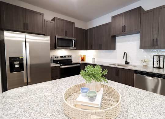 Kitchen island with granite countertops and stainless steel appliances at The Crest at South Point Apartments, McDonough