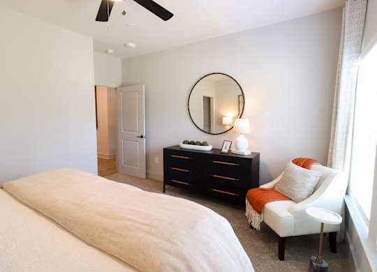 Bedroom with dresser and round mirror at The Crest at South Point Apartments, McDonough, 30253