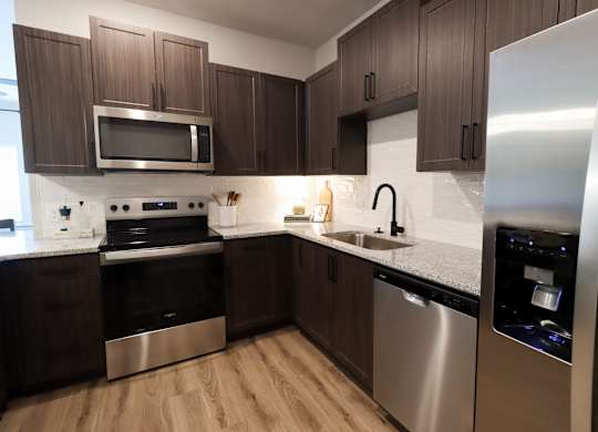 Ushaped kitchen with dark wood cabinets and stainless appliances at The Crest at South Point Apartments, Georgia