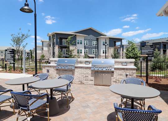 Outdoor grilling area with stone builtin bbq stations at The Crest at South Point Apartments, McDonough, 30253