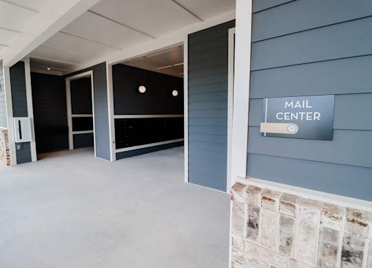 Covered parking garage with mail center and stone accent wall at The Crest at South Point Apartments, McDonough, GA 30253