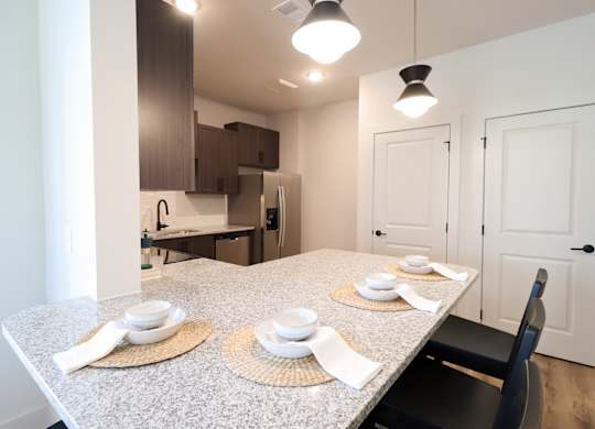 Dining area with granite peninsula and place settings at The Crest at South Point Apartments, McDonough, 30253