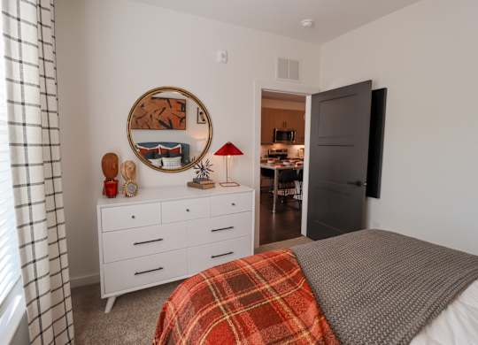 Bedroom with white dresser and round mirror at The Wren Apartments, Georgia