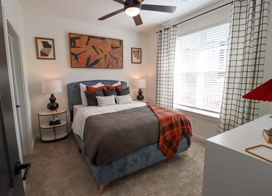 Bedroom with upholstered bed and modern decor at The Wren Apartments, Lawrenceville, GA