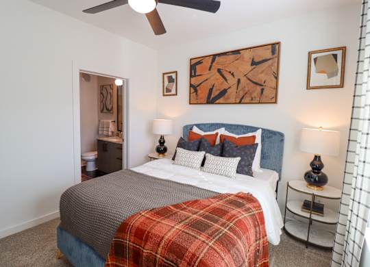 Bedroom with blue upholstered bed and ceiling fan at The Wren Apartments, Georgia, 30043