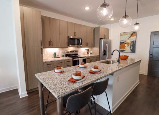 Modern kitchen with granite island seating for four at The Wren Apartments, Lawrenceville, GA