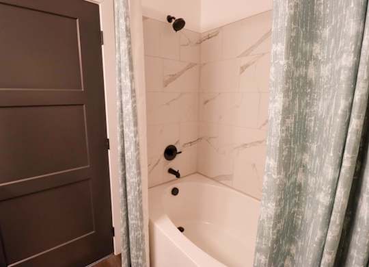 Bathroom with soaking tub and marble tile surround at The Wren Apartments, Georgia, 30043