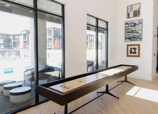Shuffleboard table in community game room with wall art at The Wren Apartments, Lawrenceville, GA 30043