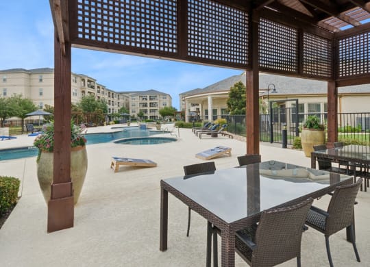 outdoor patio with corn hole game and shaded dining area at Retreat at Wylie senior 55+ apartments