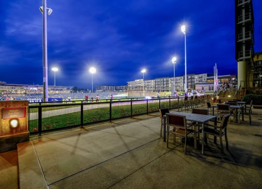 a terrace with tables and chairs overlooking a race track at night