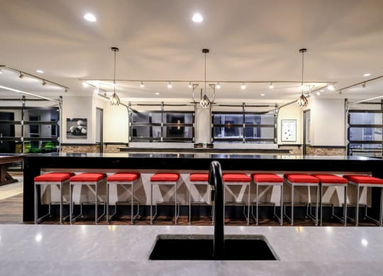a large kitchen with a long bar with red stools