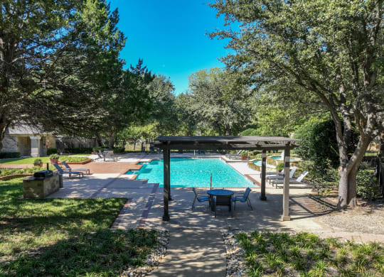 a resort-inspired swimming pool surrounded by lush landscaping at Stoneleigh on Spring Creek apartments