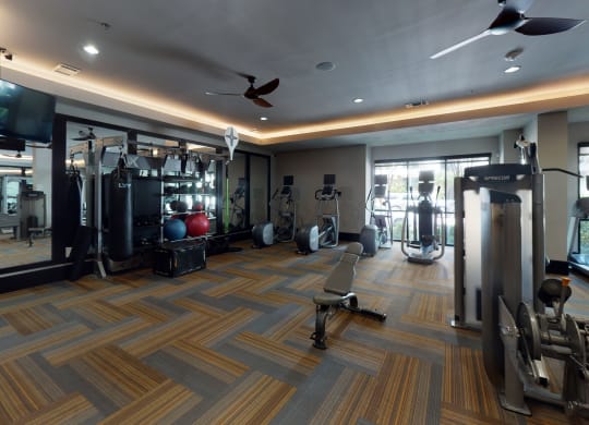 a spacious fitness room with cardio equipment and a flat screen tv