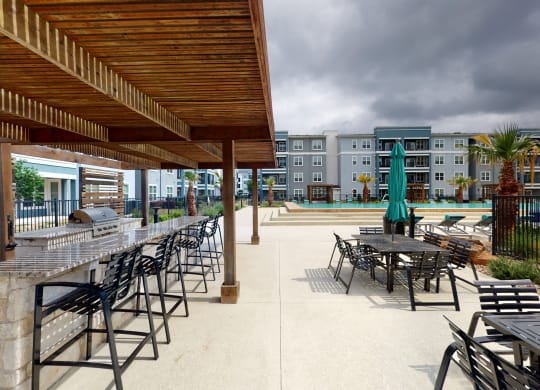 a patio with tables and chairs and a pool in the background