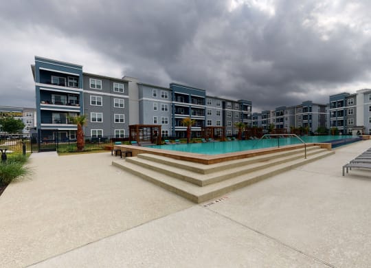 a large swimming pool in front of an apartment building