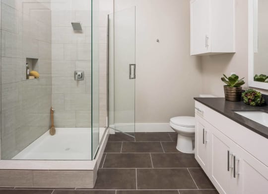 spacious bathroom with glass framed shower doors at Tinsley on the Park apartments