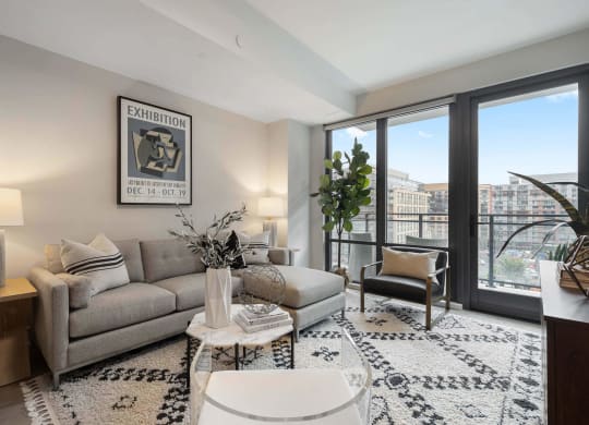 an open living room with a couch and large windows in Tribeca NOMA apartments