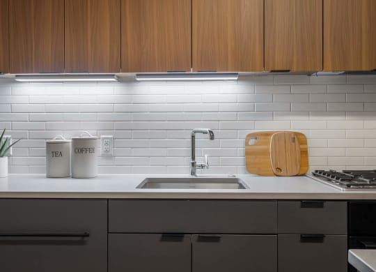 A white kitchen counter with a sink and wooden cabinets at Tribeca NOMA apartments