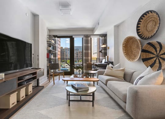 a living room with a couch and a tv and a balcony at Tribeca NOMA apartments