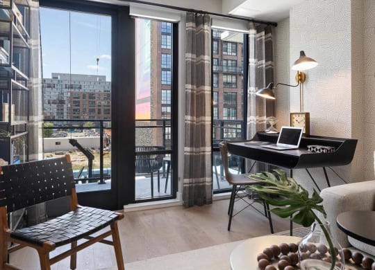 a living room with a black desk and a view of a balcony at Tribeca NOMA apartments