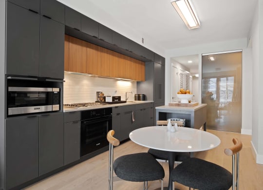 a kitchen with black cabinets and a table and chairs at Tribeca NOMA apartments