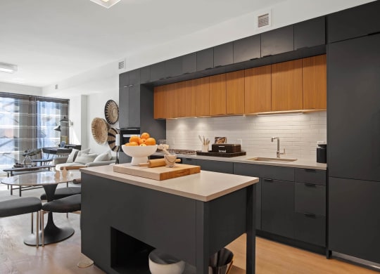 a kitchen with black cabinets and a counter with a bowl of fruit at Tribeca NOMA apartments