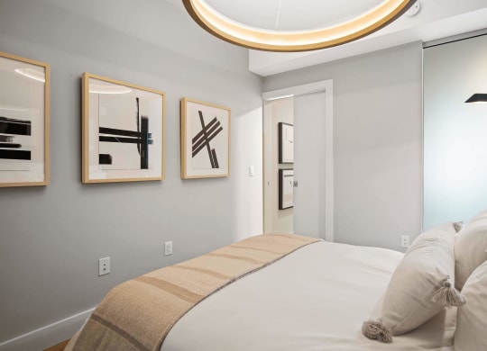 a bedroom with a bed and modern light fixture at Tribeca NOMA apartments