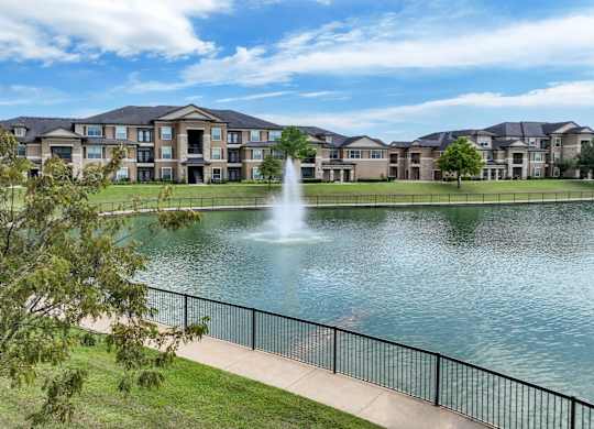 pathway near the lake with a fountain at The Falls at Copper Lake apartments