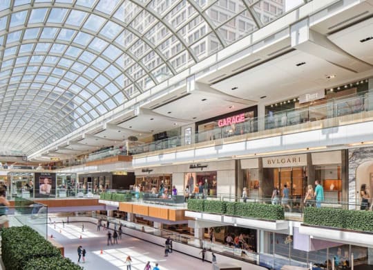 a shopping mall with glass ceilings and people walking