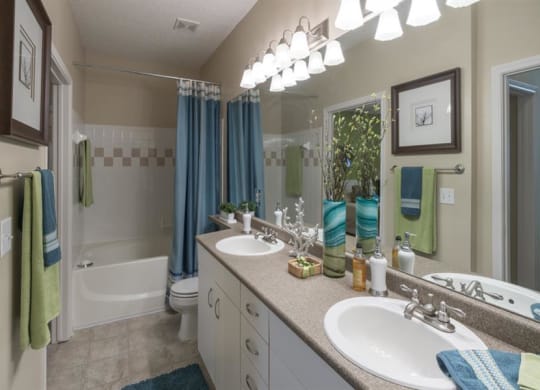 Master bathroom with floating vanities, quartz countertops, backlit vanity mirror, walk-in shower with Euro shower door and quartz-topped bench seat at Wyndchase  Aspen Grove, Tennessee, 37067