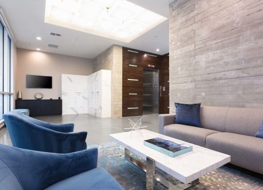 Indoor common area with blue armchairs and grey sofa at Lyric, Walnut Creek, CA