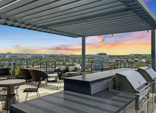 a rooftop terrace with a grill and a view of the city at sunset at Tribeca NOMA apartments