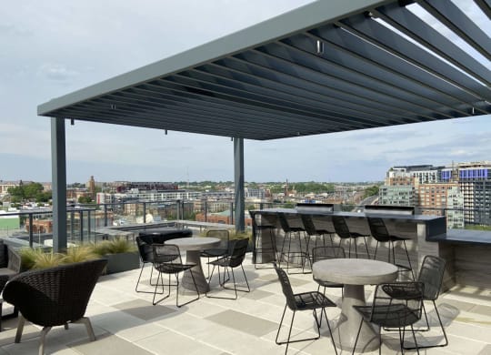a rooftop patio with tables and chairs and a view of the city at Tribeca NOMA apartments