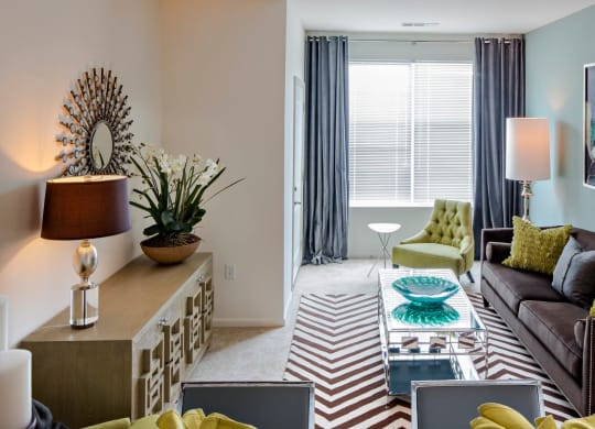 a living room with a couch and table and large window at Reveal Hackensack apartments
