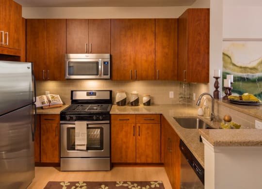 a kitchen with stainless steel appliances and wooden cabinets at Reveal Hackensack apartments