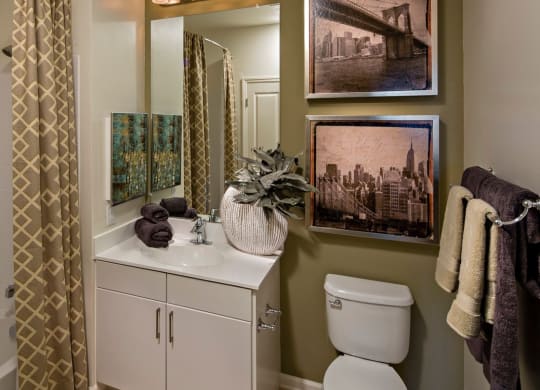a bathroom with a toilet and a sink and a shower in Reveal Hackensack apartments