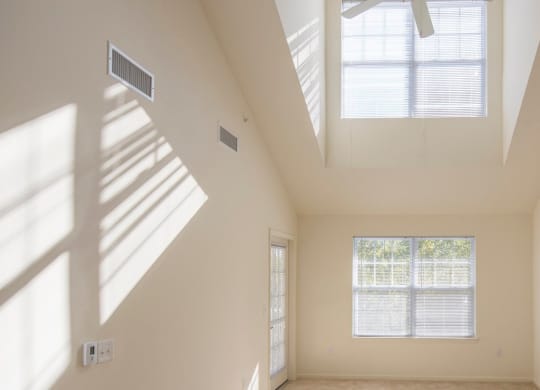 a living room with two windows and a high ceiling at Reveal Hackensack apartments