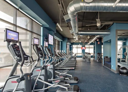 a gym with cardio equipment and weights in Reveal Hackensack apartments