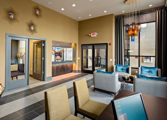 a lobby with tables and bright chairs at Reveal Hackensack apartments