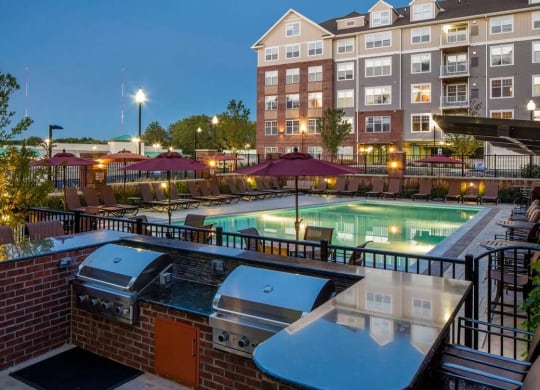 a grilling area and pool at Reveal Hackensack apartments in Hackensack New Jersey