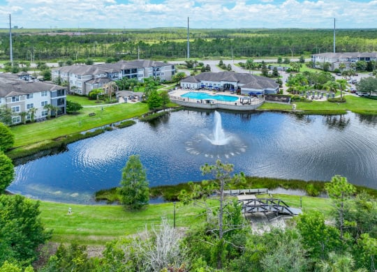 aerial view of lake with a fountain and a pool in the background at The Reserves at Alafaya apartments