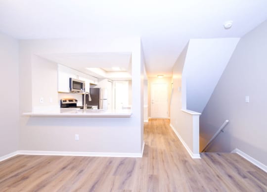 a spacious living area with hardwood floors and a kitchen in the background