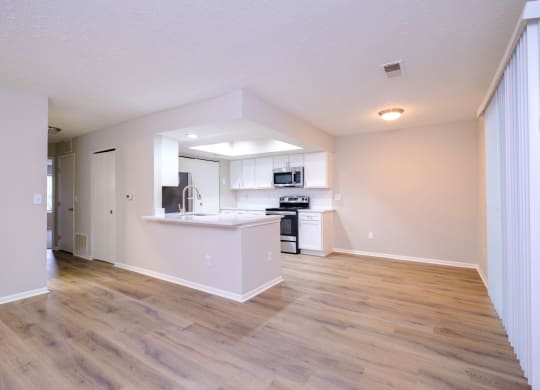 a spacious living room with a kitchen in the background