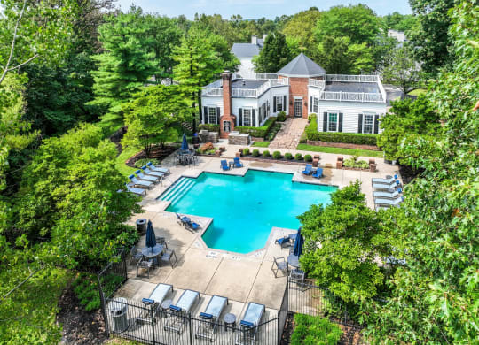 an aerial view of a resort style swimming pool with lounge chairs and umbrellas