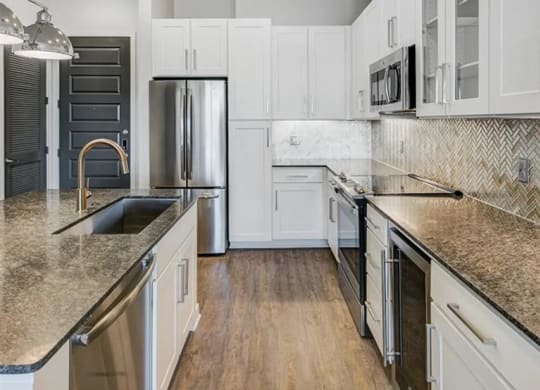 a kitchen with white cabinets and a stainless steel appliances at The Gabriella apartments