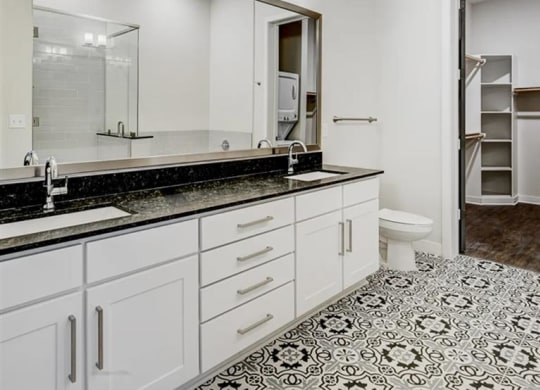 a bathroom with white cabinets and designer lighting at The Gabriella apartments