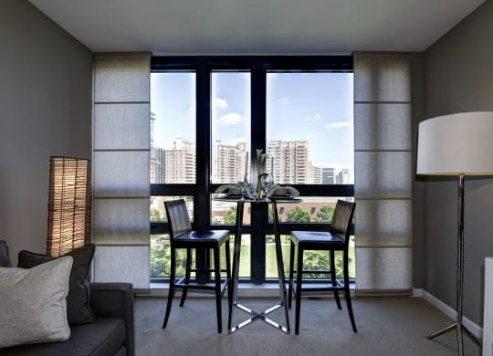 a dining area with a table and four chairs in front of a large window at The Millennium, Virginia