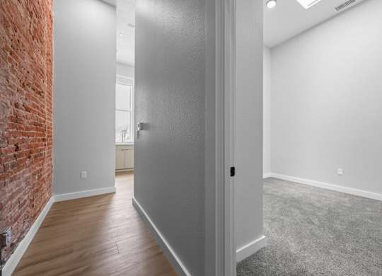 A room with a grey door and a brick wall on the left side at The Avenue Lofts Golden Apartments, Colorado