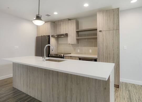 A modern kitchen with a white countertop and wooden cabinets at The Avenue Lofts Golden Apartments, Colorado